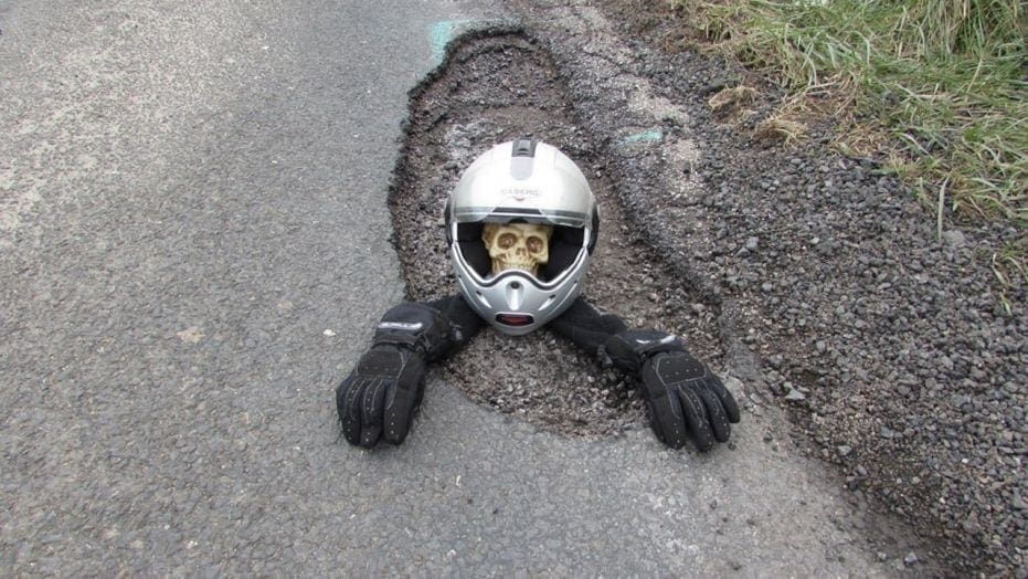 Pothole Protest: Biker buries helmet-wearing skeleton